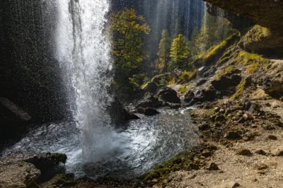 Fotografija slapu, kjer fotograf stoji za slapom in fotografira proti opazovalni ploščadi.